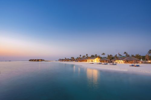 Free Beautiful island resort in the Maldives with white sand beaches and serene turquoise waters at sunset. Stock Photo