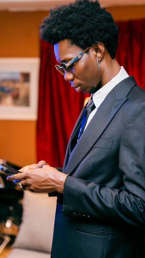 Free Stylish young adult in suit using smartphone indoors for business communication. Stock Photo