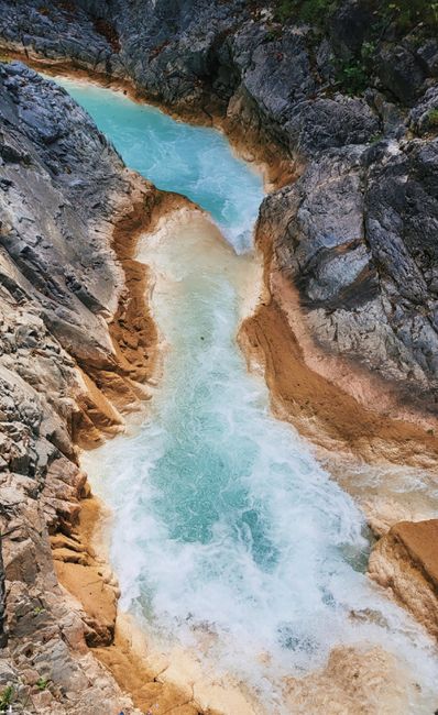 Aerial perspective of a vivid blue river flowing through rocky terrain, showcasing natural beauty.