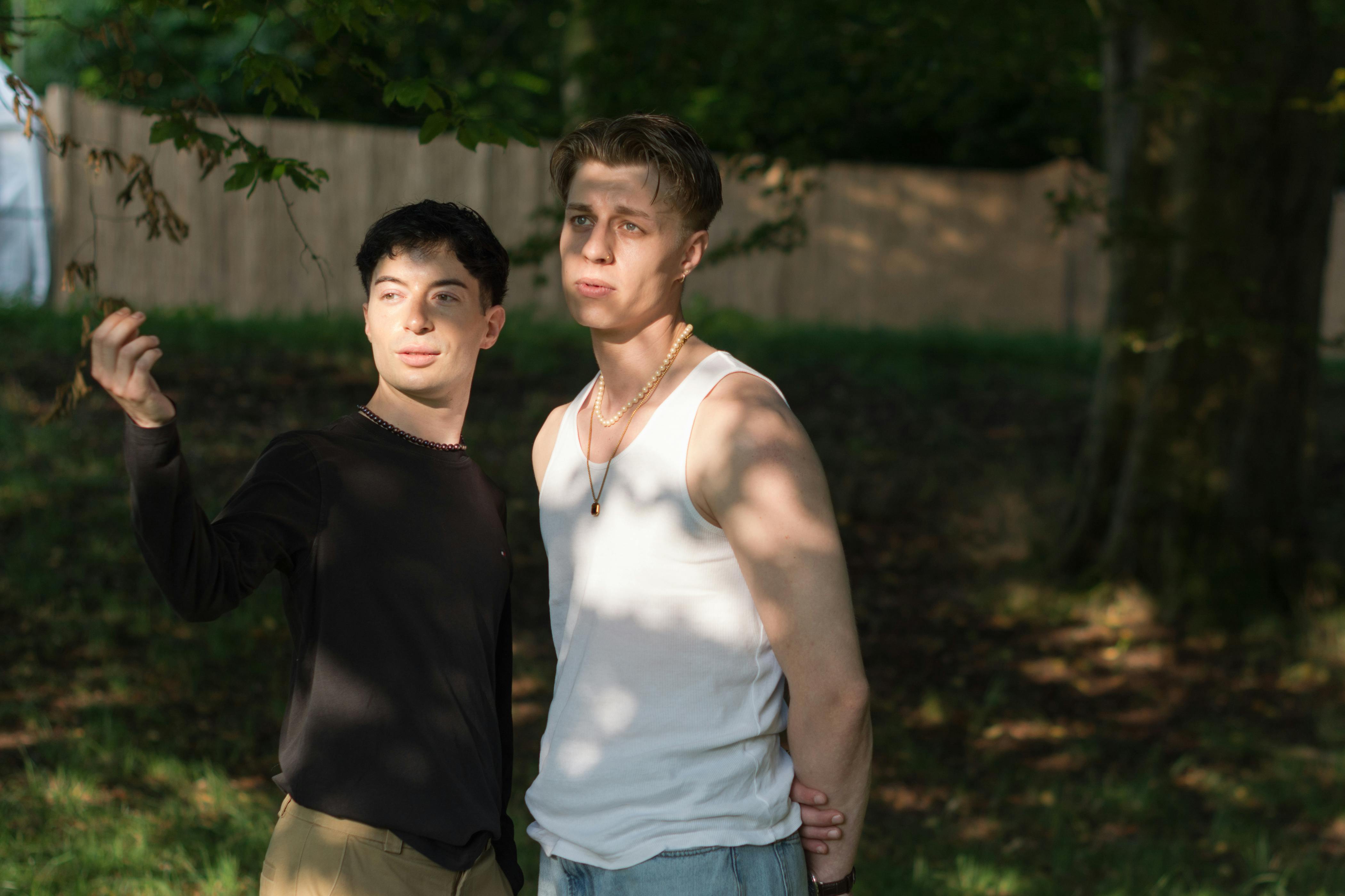Two young men enjoying a sunny day outside, expressing joy and contemplation.