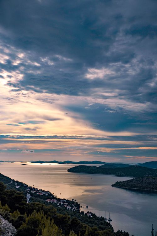 Free A breathtaking aerial view of a tranquil lake surrounded by hills, captured at sunset with vibrant colors. Stock Photo