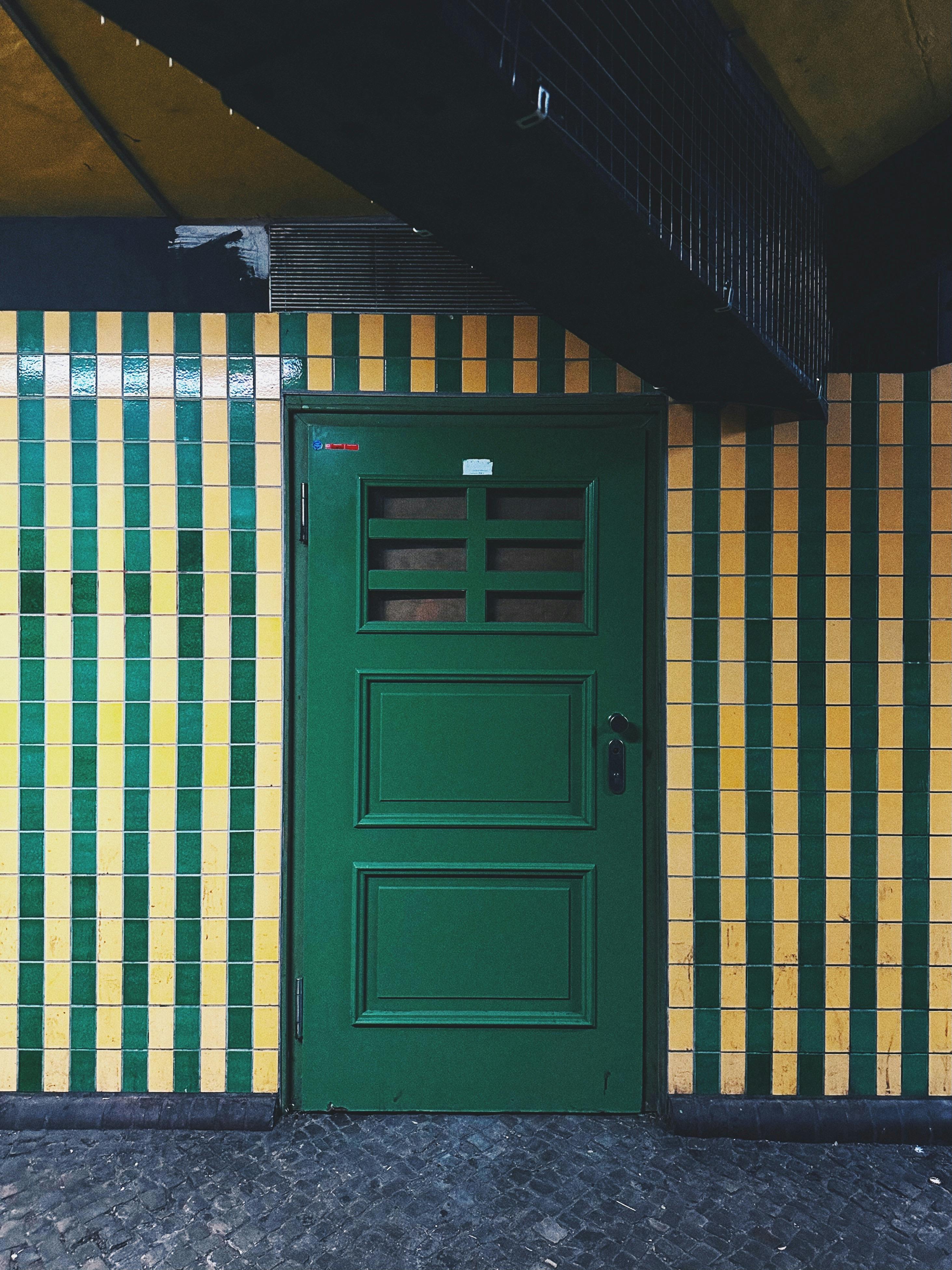 Bright yellow and green tiled wall with door in Berlin station, showcasing geometric patterns.