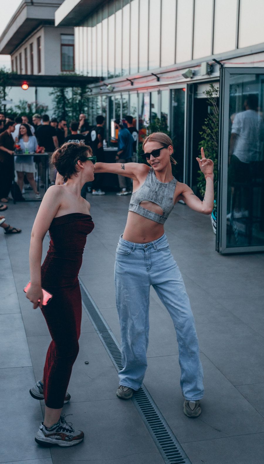 Young adults dancing and laughing at an outdoor rooftop social event