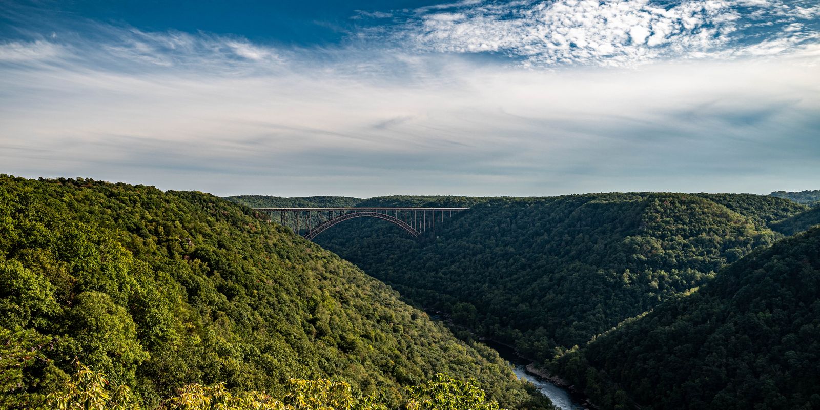 Breathtaking view of lush green mountains with a bridge in the distance