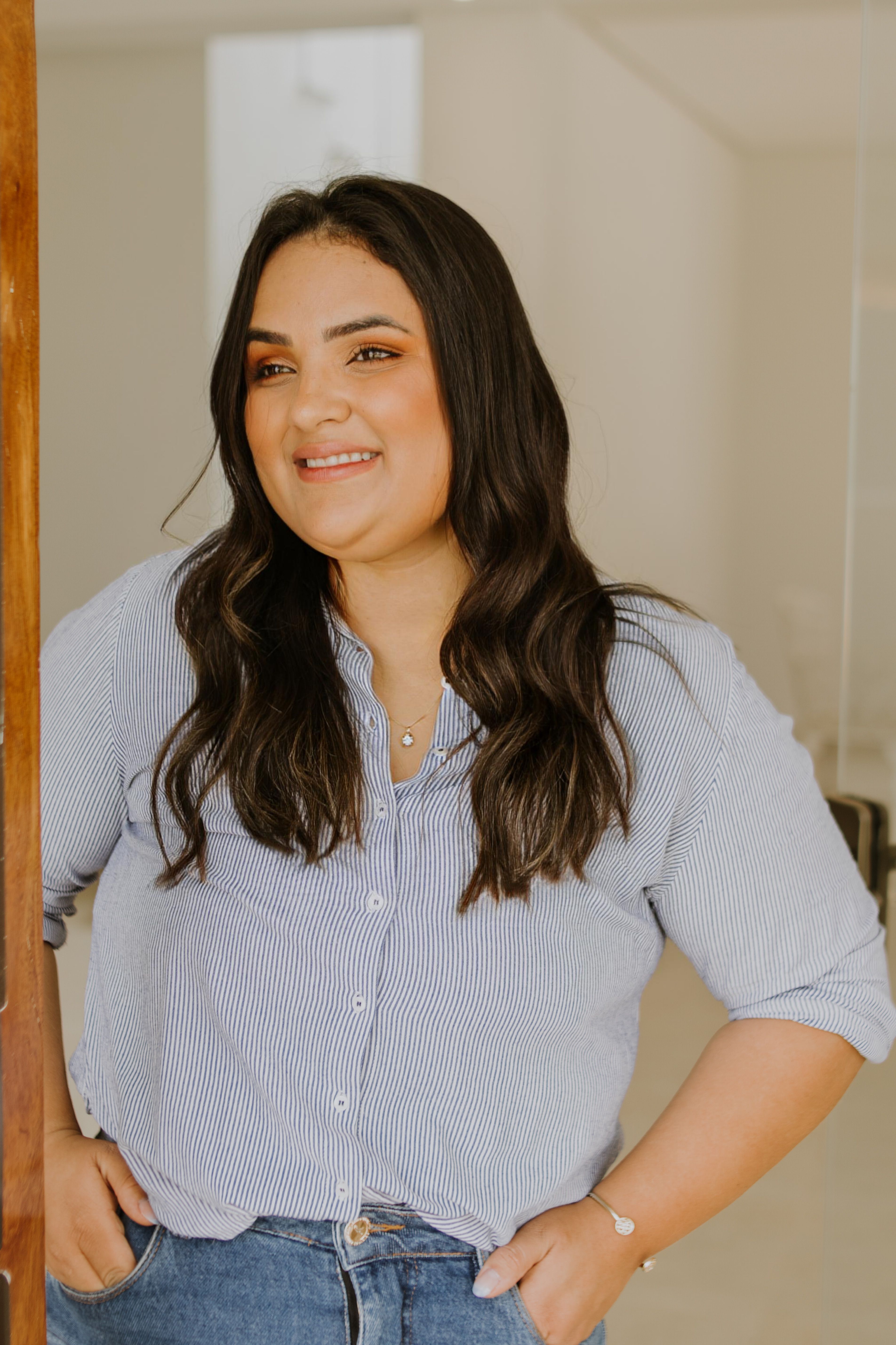 Smiling woman in a striped shirt standing confidently indoors.