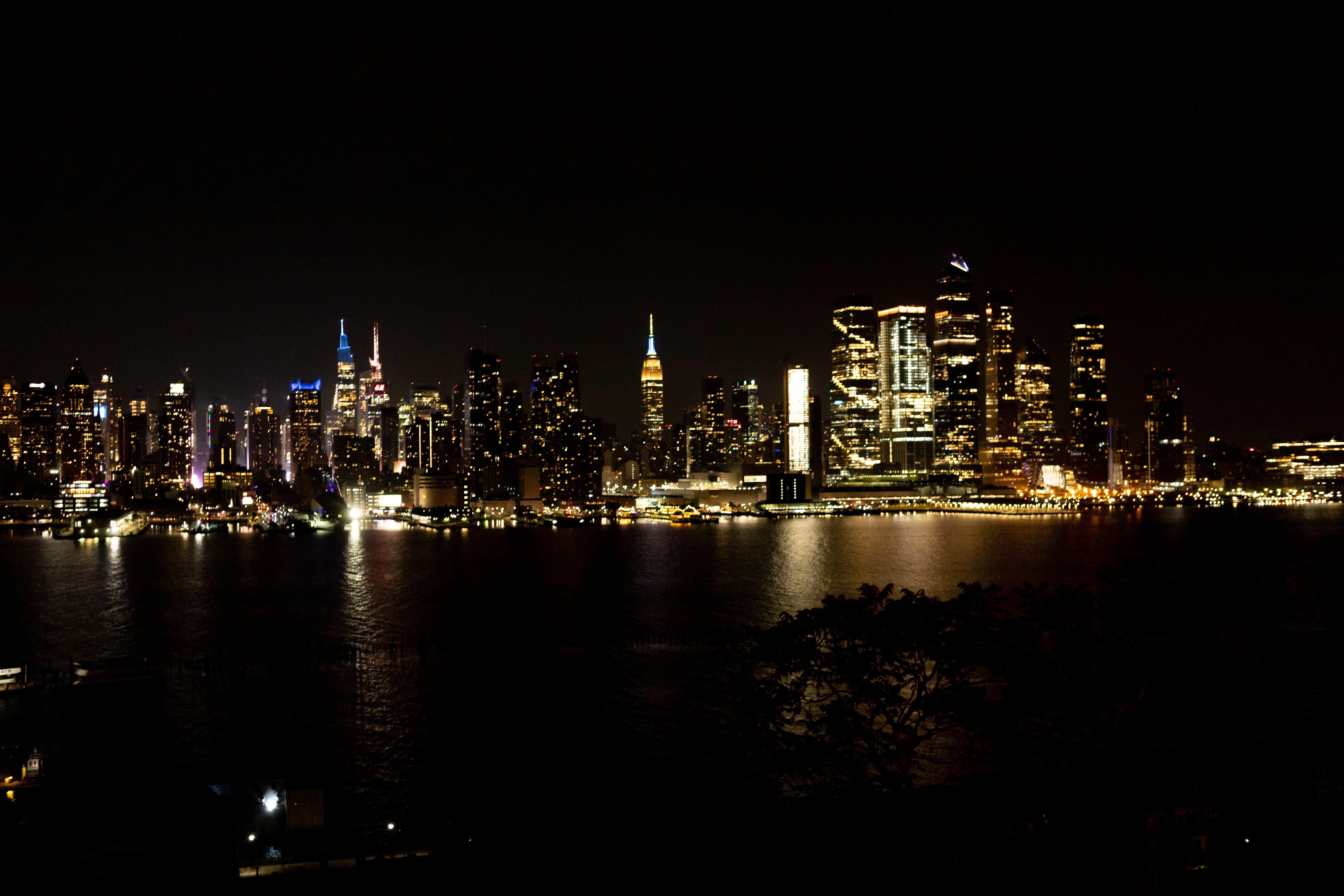 New York City skyline lit up at night reflecting in the Hudson River