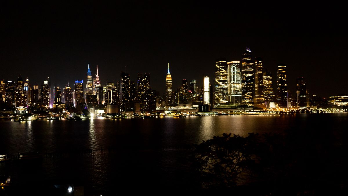 New York City skyline lit up at night reflecting in the Hudson River