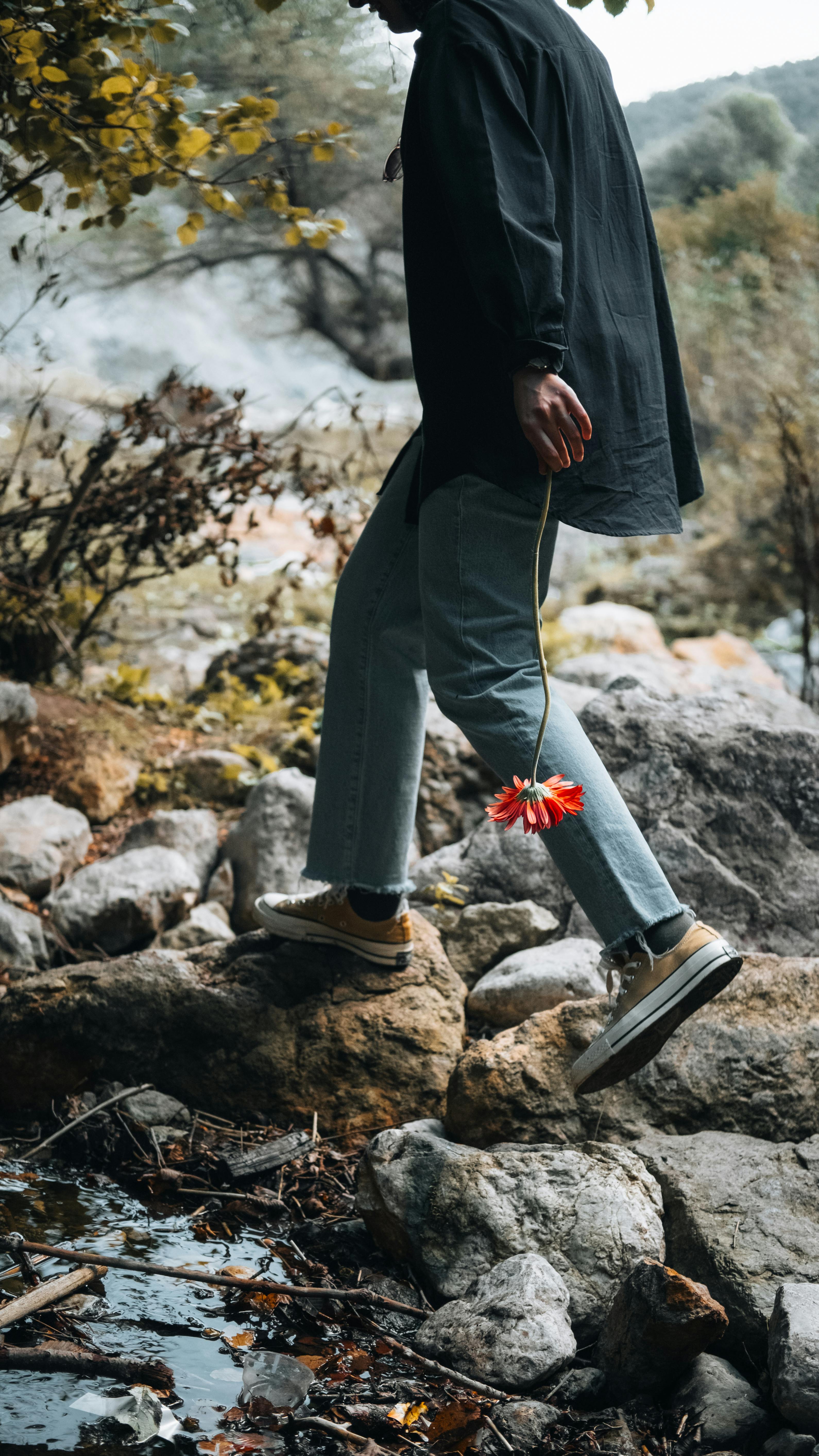 young adult walking with red flower in hand