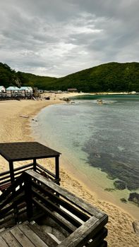 Capture of a serene beach with crystal clear water and scenic hills in the background.