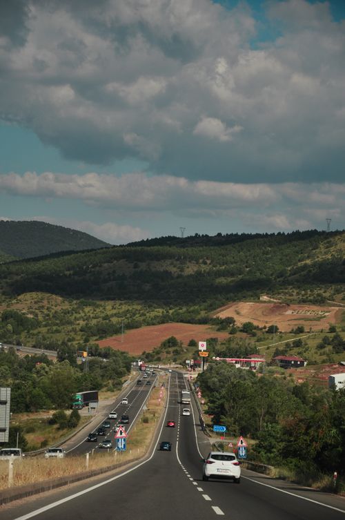 Free Highway leading through lush green mountains under cloudy skies, offering a scenic drive. Stock Photo