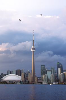 Beautiful evening view of Toronto skyline featuring CN Tower and cityscape under cloudy skies.