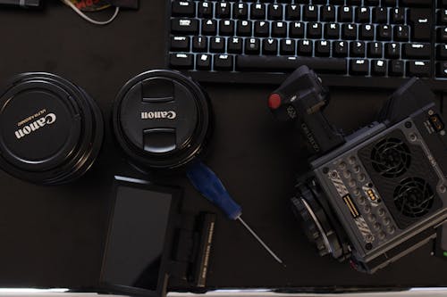Canon Camera Lens Covers Beside Screwdriver and Computer Keyboard