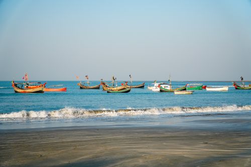 Free Colorful fishing boats float on calm blue waters near a peaceful tropical beach. Stock Photo