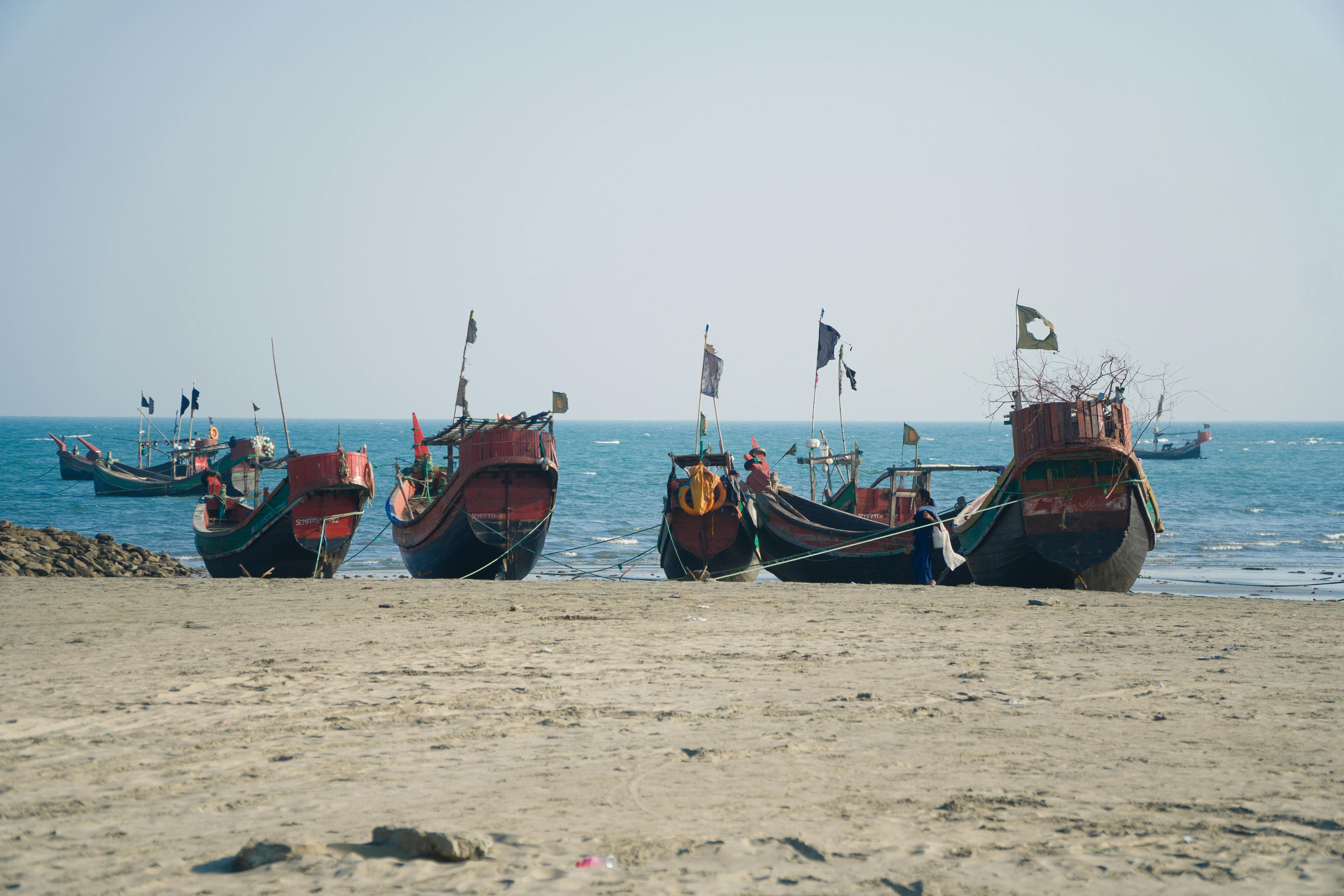 Traditional fishing boats resting on a secluded beach in Bangladesh, offering a glimpse of coastal life.
