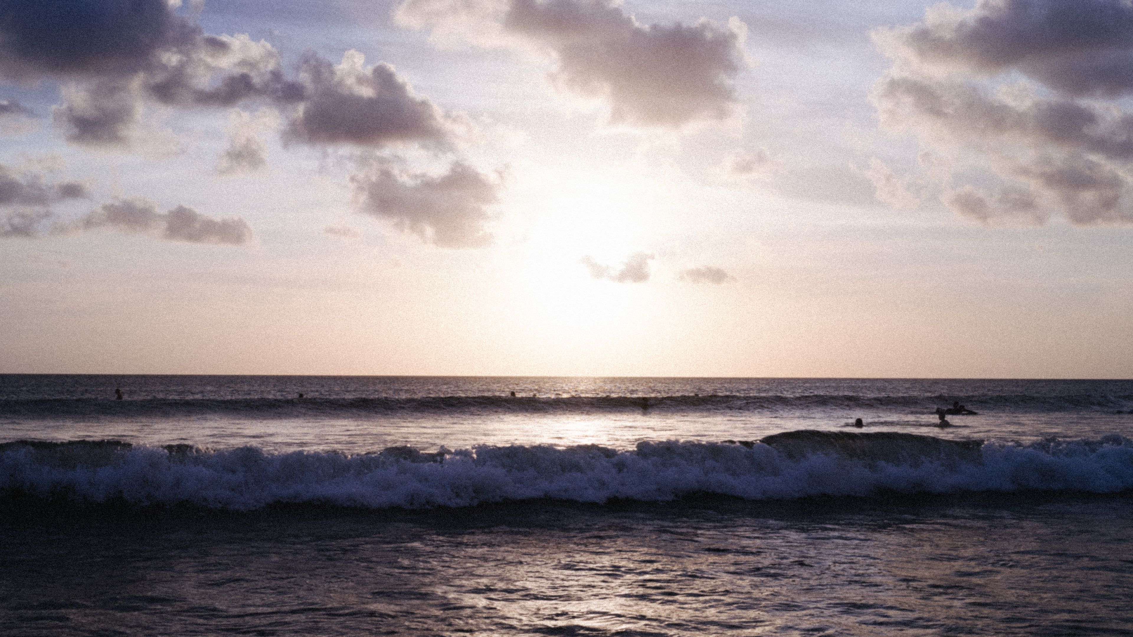 Enjoy a stunning sunset over the waves at Kuta Beach, Bali, perfect for surfing and relaxation.