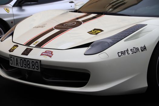 Detailed view of a sports car with decals and racing stripes, parked outdoors.