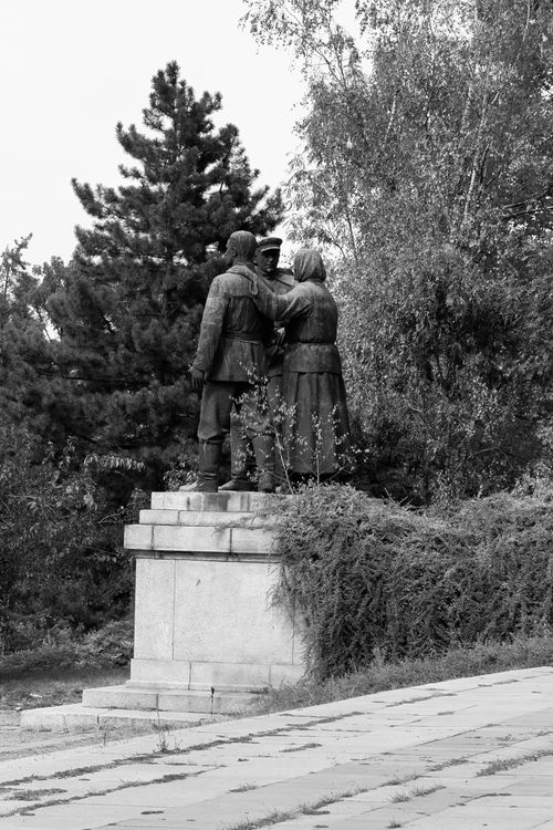Free Black and white image of a classic sculpture in a lush park featuring three figures. Stock Photo