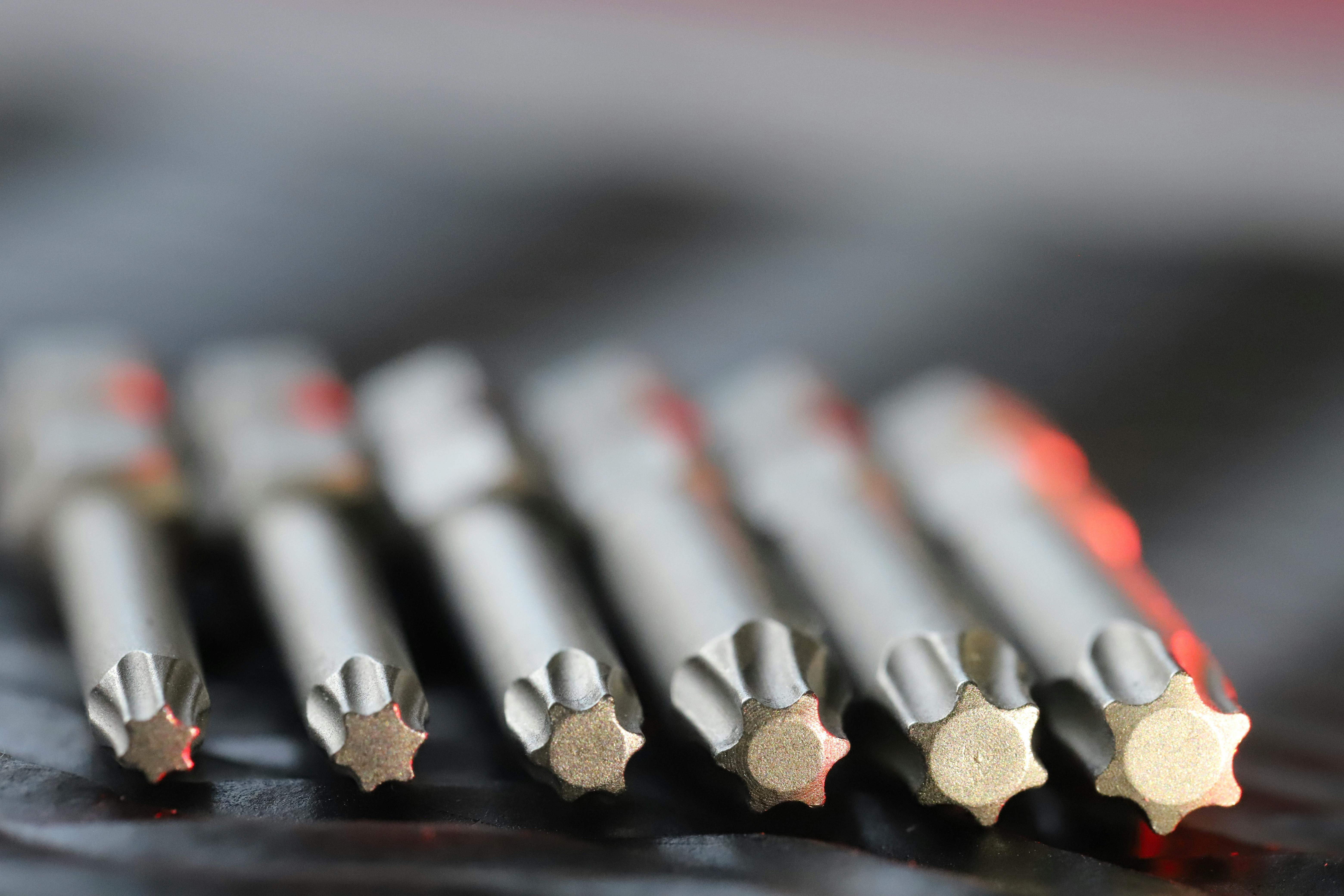 Macro shot of metal precision drill bits with star-shaped tips in a row, emphasizing detail and craftsmanship.