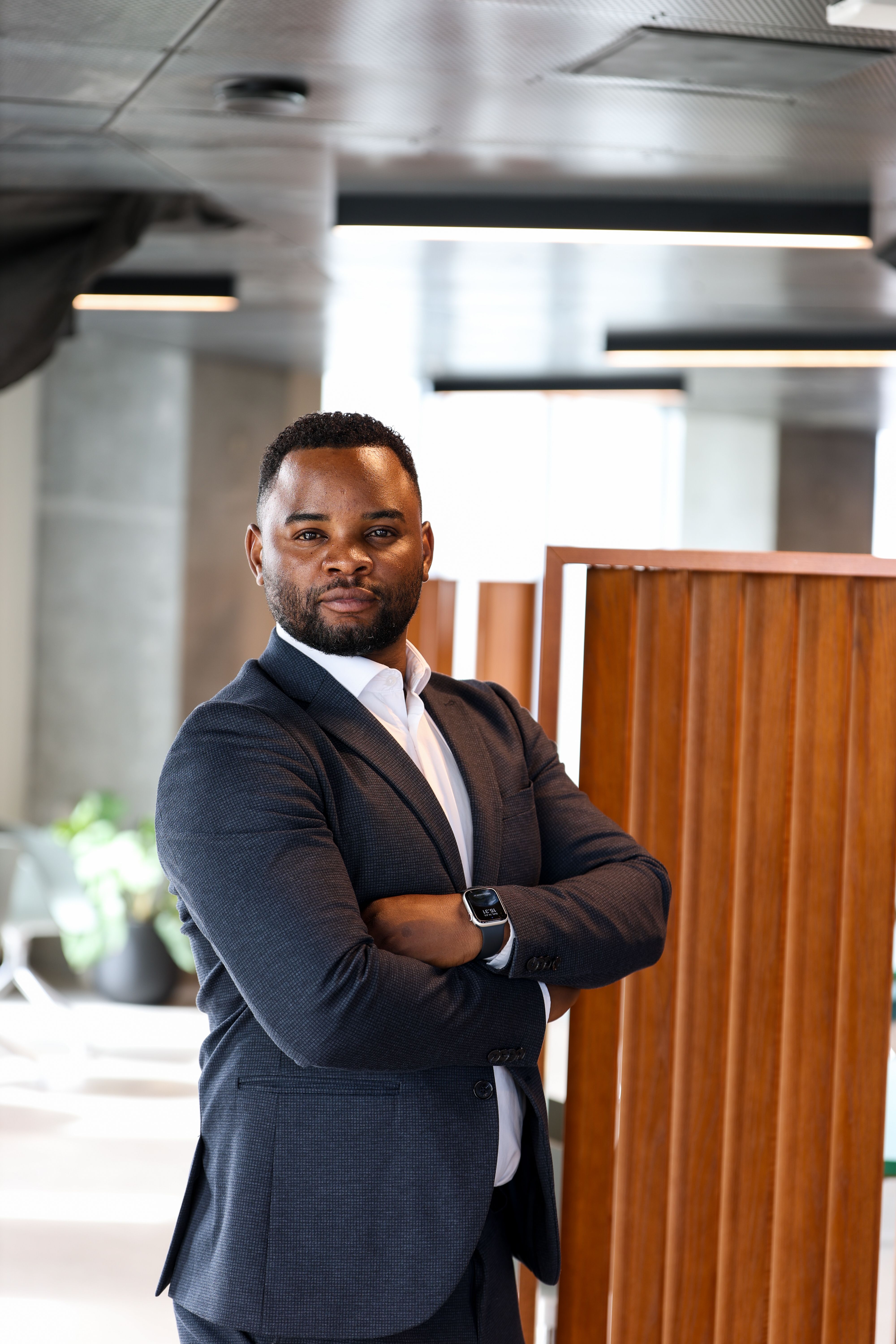 Businessman standing confidently in a modern office with folded arms, exuding professionalism.