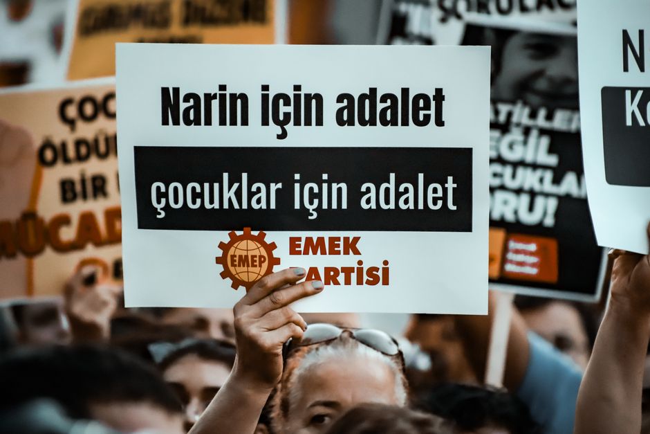 A crowd holds signs advocating for justice and children's rights at a protest.