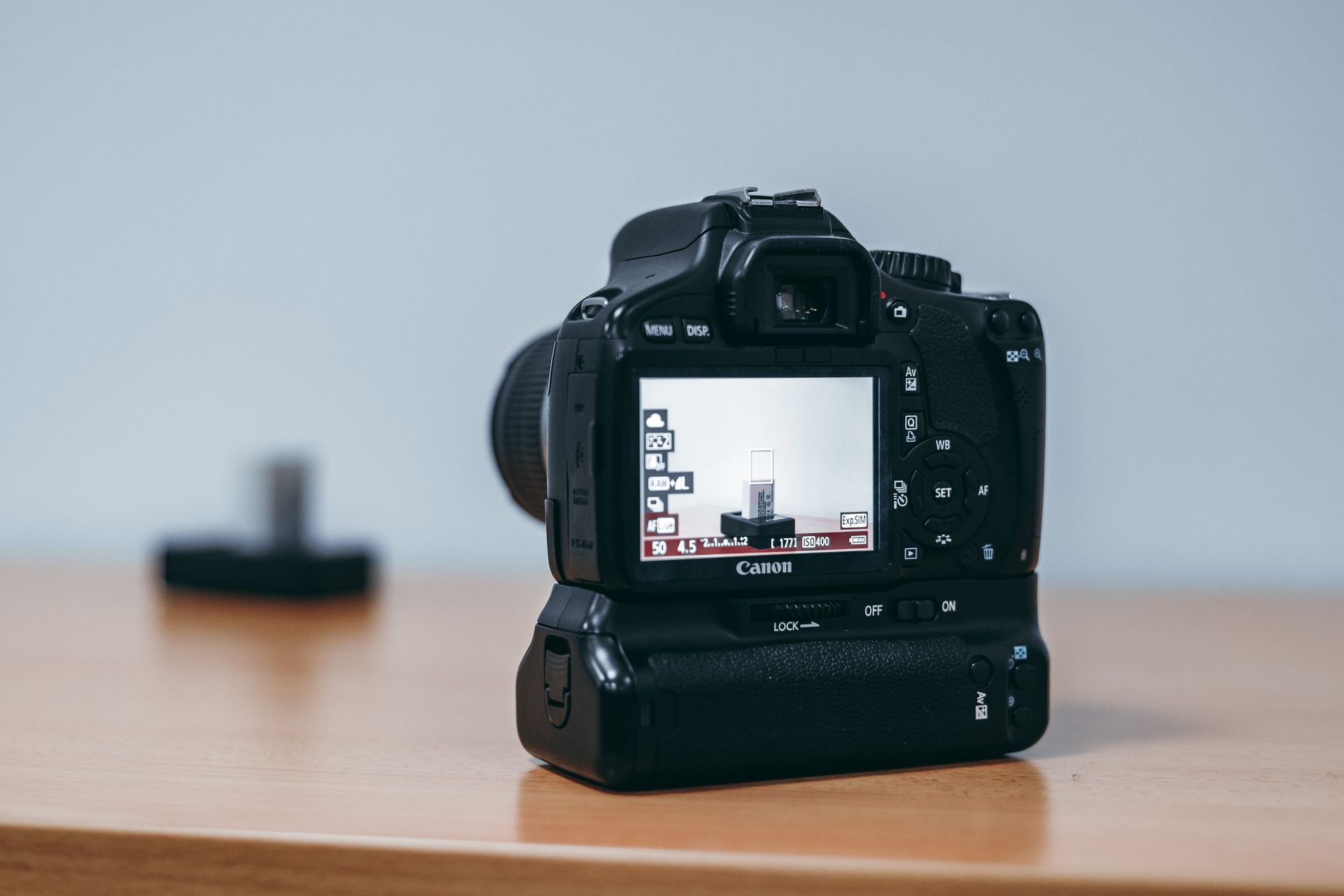 Close-up of a DSLR camera with LCD screen visible, resting on a desk.