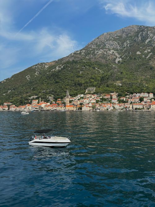 Free A serene view of a boat on Montenegro's coastline with lush mountains and clear skies. Stock Photo