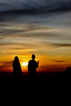 Two people silhouetted against a beautiful orange and blue sunset sky.