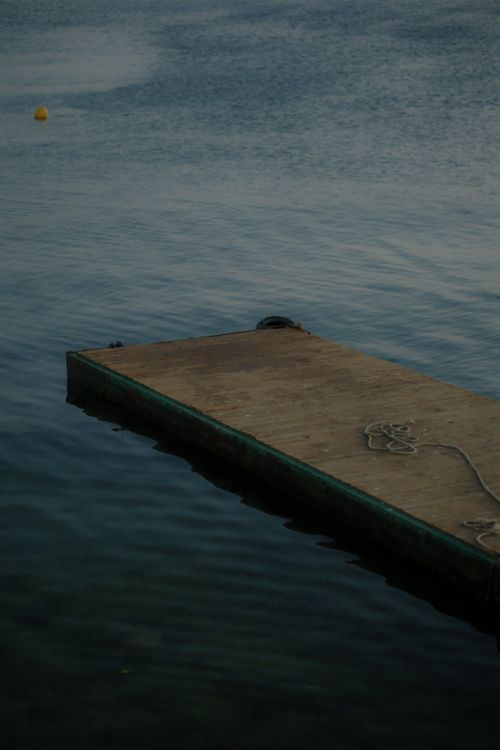 Free Tranquil scene of a wooden dock floating on calm lake waters during sunset. Stock Photo
