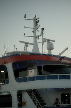 Upper deck of a luxury yacht with radar equipment and lights at twilight.