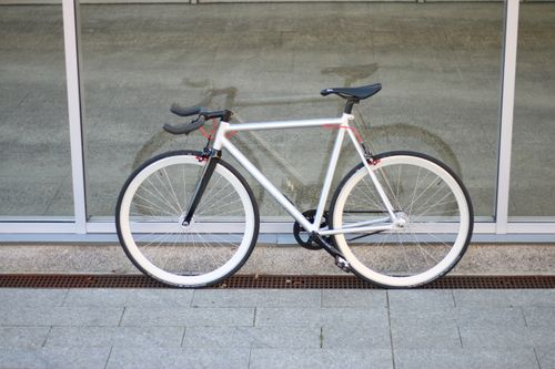 Free Sleek fixed gear bicycle leaning against a glass wall, showcasing urban minimalist design. Stock Photo