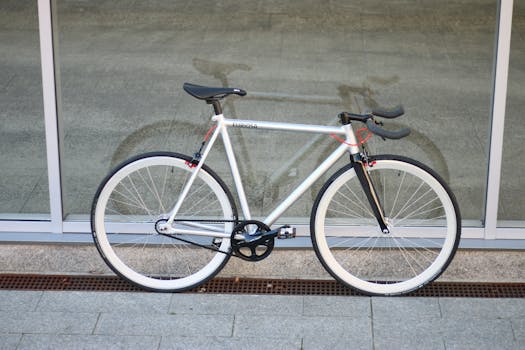 Sleek single-speed bicycle resting against a modern glass wall, showcasing its minimalist design.
