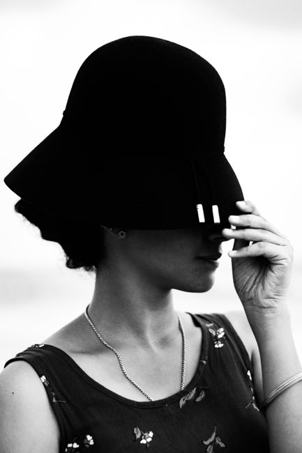 Stylish monochrome portrait of a woman wearing a fashionable hat, exuding elegance and mystery.