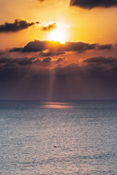 日落迷人，宁静的海面上映着戏剧性的云层与光线