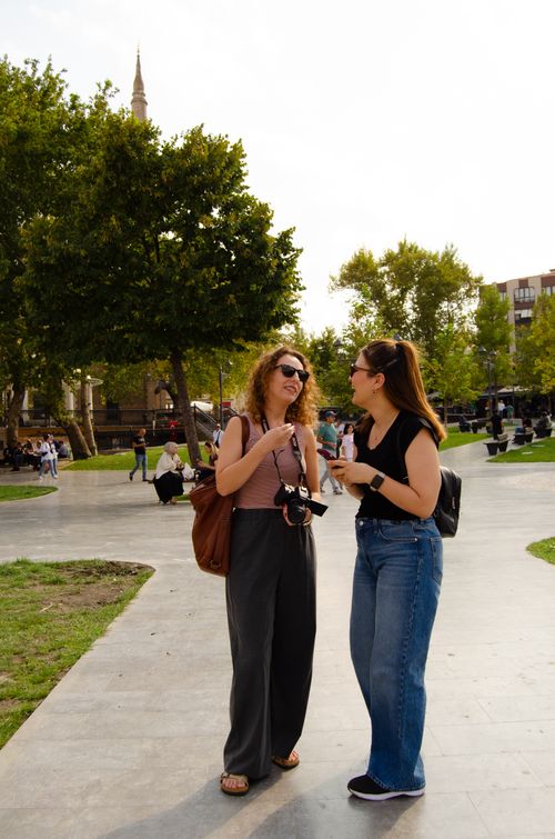 Free Two women share a moment in a lively city park under a clear sky. Stock Photo