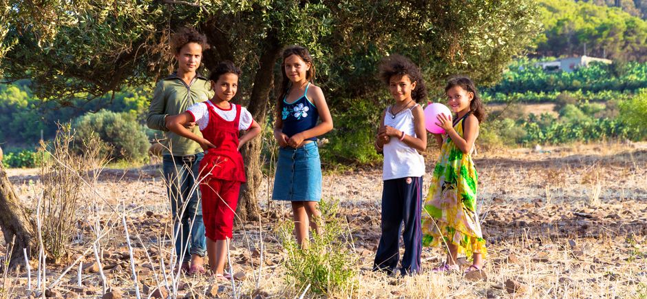 Grupo de niños disfrutando de un día juguetón en el campo tunecino rodeado de naturaleza.