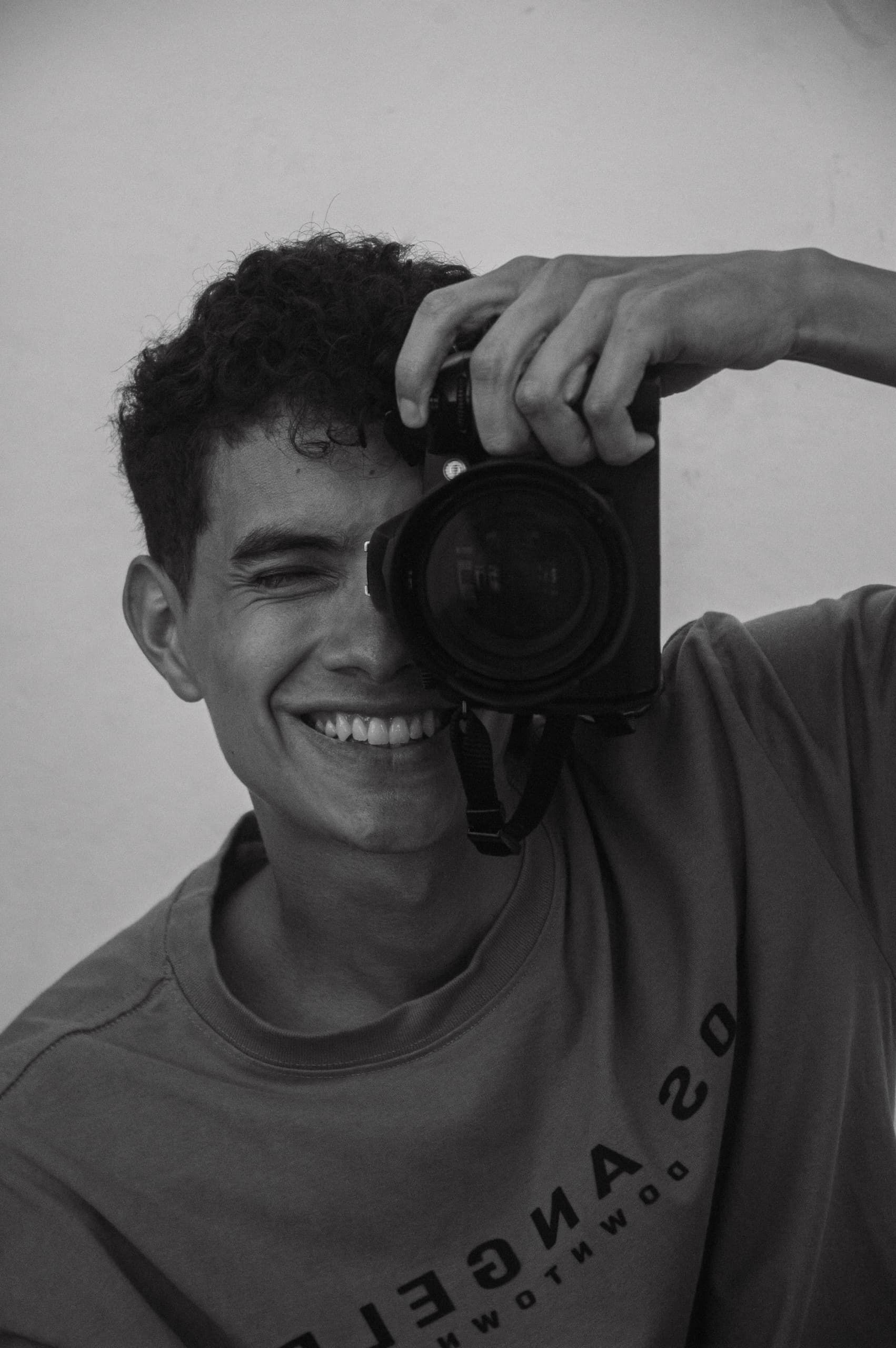 Portrait of a young photographer smiling while holding a camera.