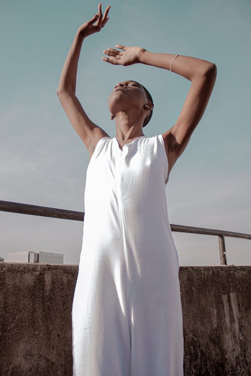 Foto De Mulher Vestida De Branco Posando Com A Cabeça Para Cima E As Mãos Levantadas