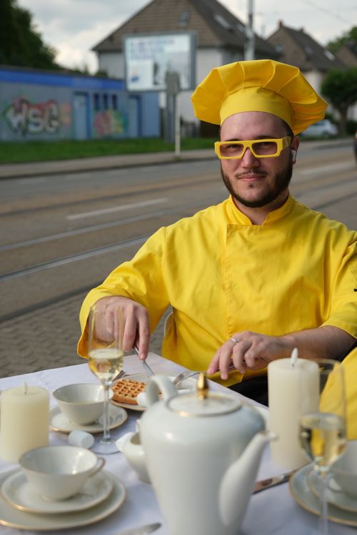 Free Bearded chef in yellow uniform dining outdoors with elegant tableware set up. Stock Photo