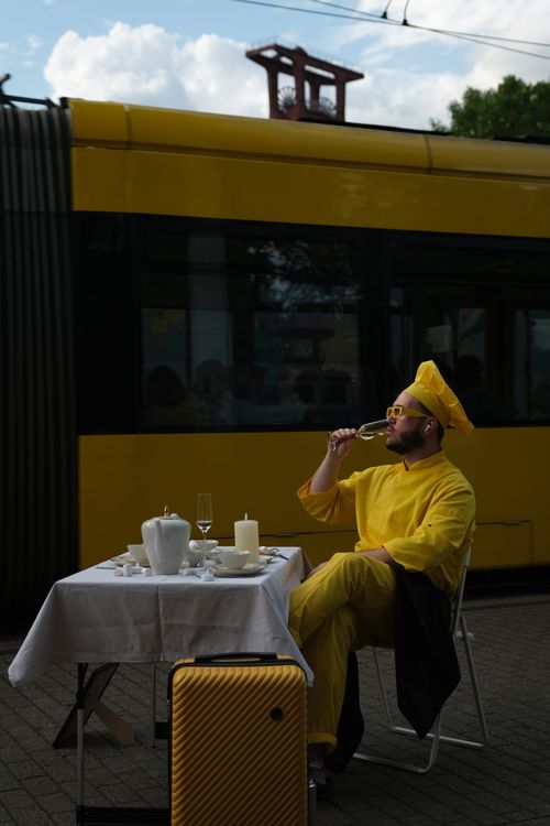 Free Man in yellow suit drinks by a tram, creating a vivid street scene in Essen, Germany. Stock Photo