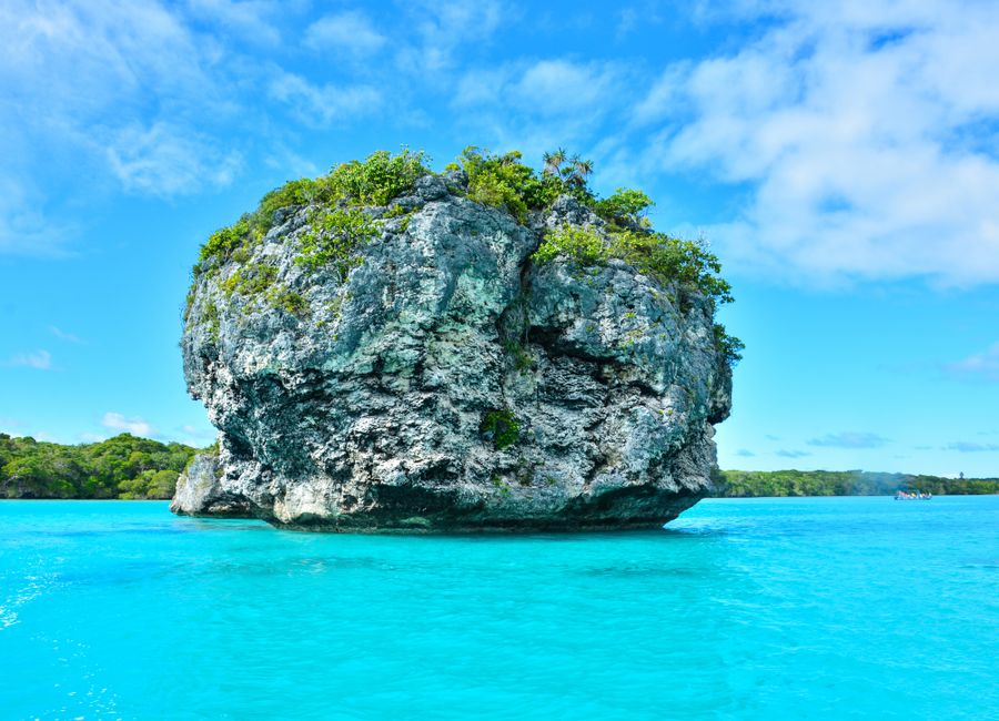 Vibrant turquoise waters and lush rock formations in Nouméa, New Caledonia.