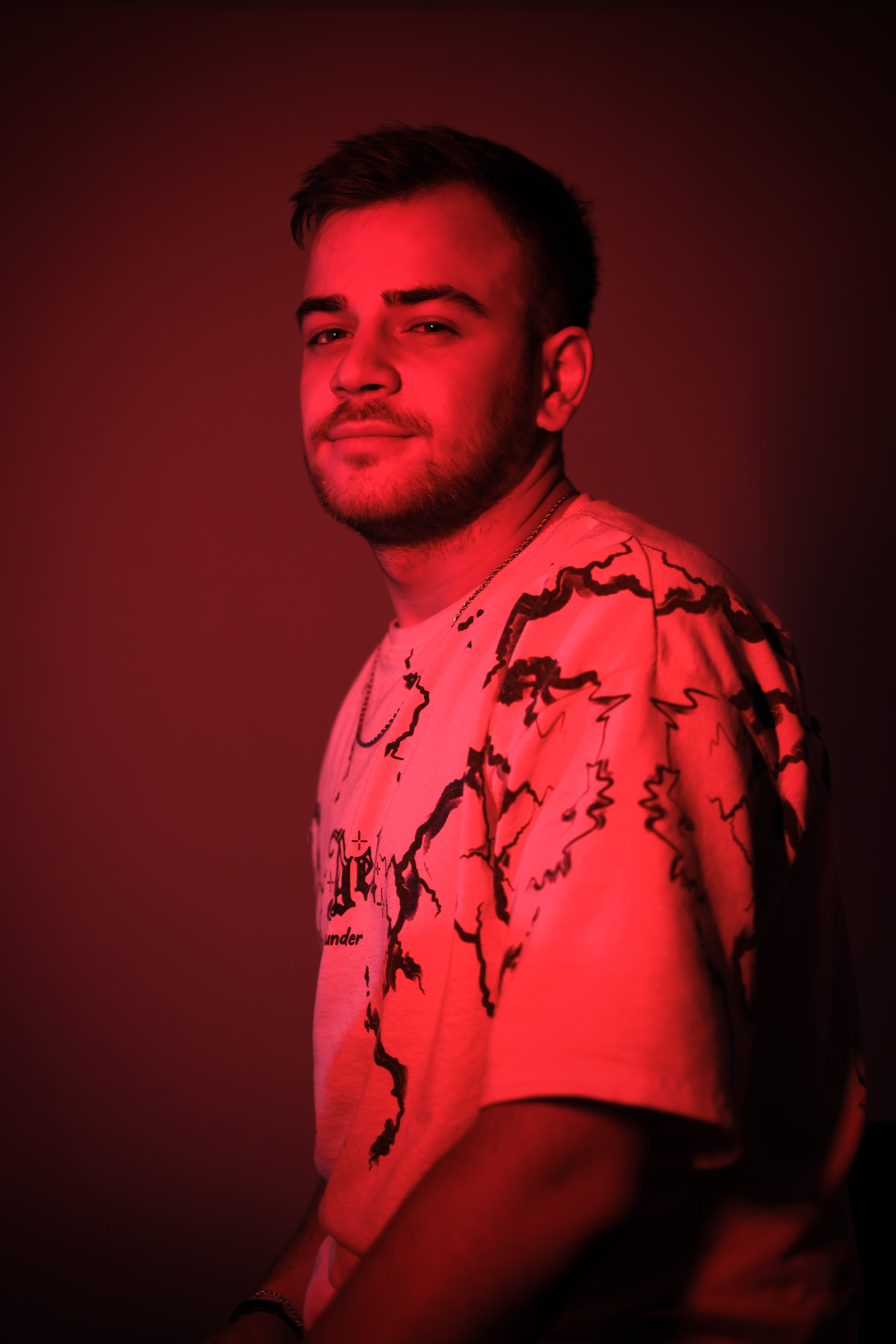 Portrait of a young man with red lighting, emphasizing a creative and edgy vibe.