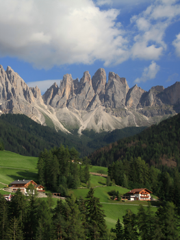 Scenic view of Dolomite peaks and a tranquil Alpine village on a sunny day.