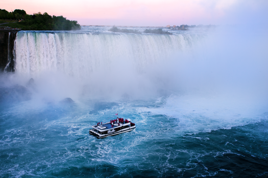 Tour boat near the majestic Niagara Falls at sunset, showcasing natural beauty.