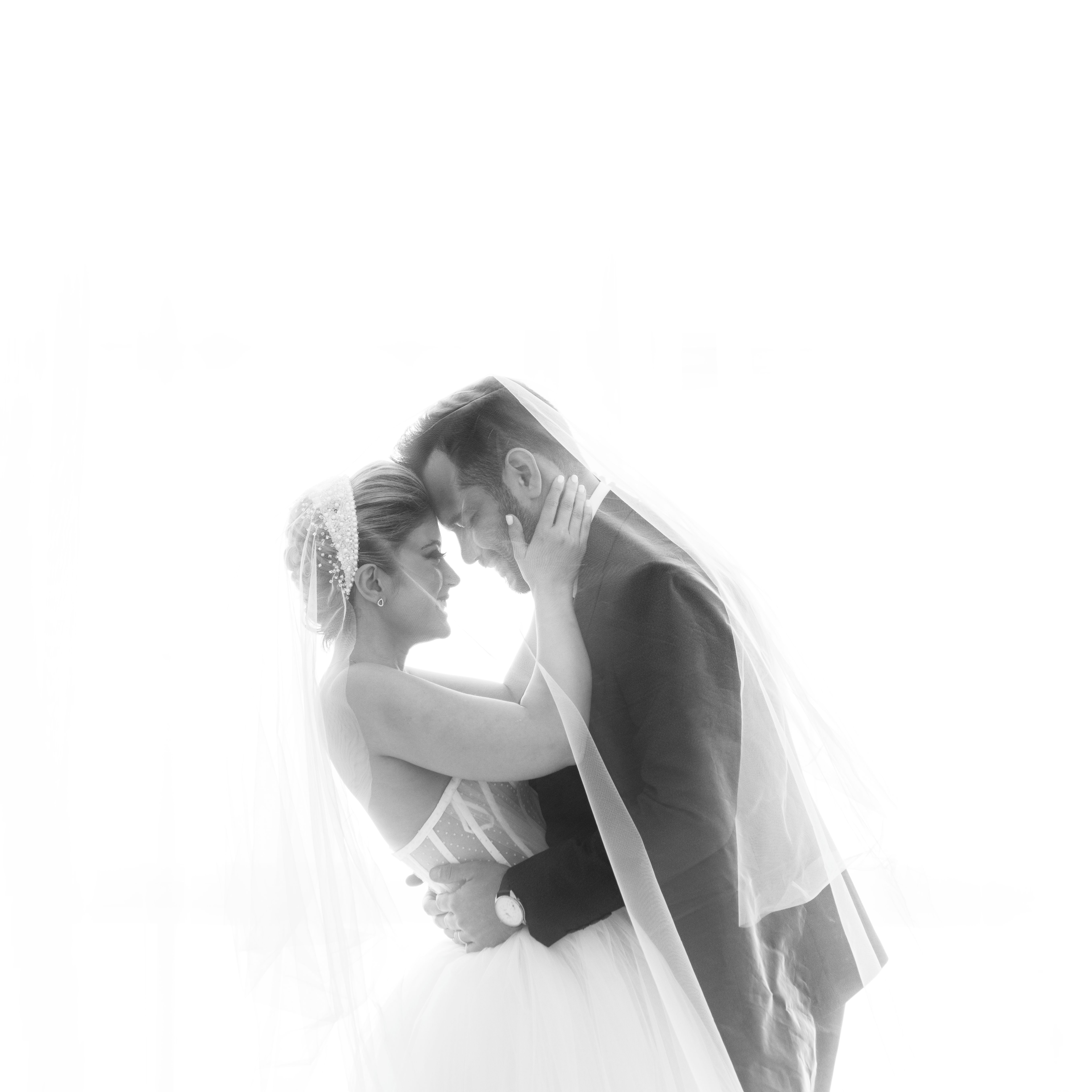 A romantic black and white bride and groom embrace, capturing a timeless wedding moment.
