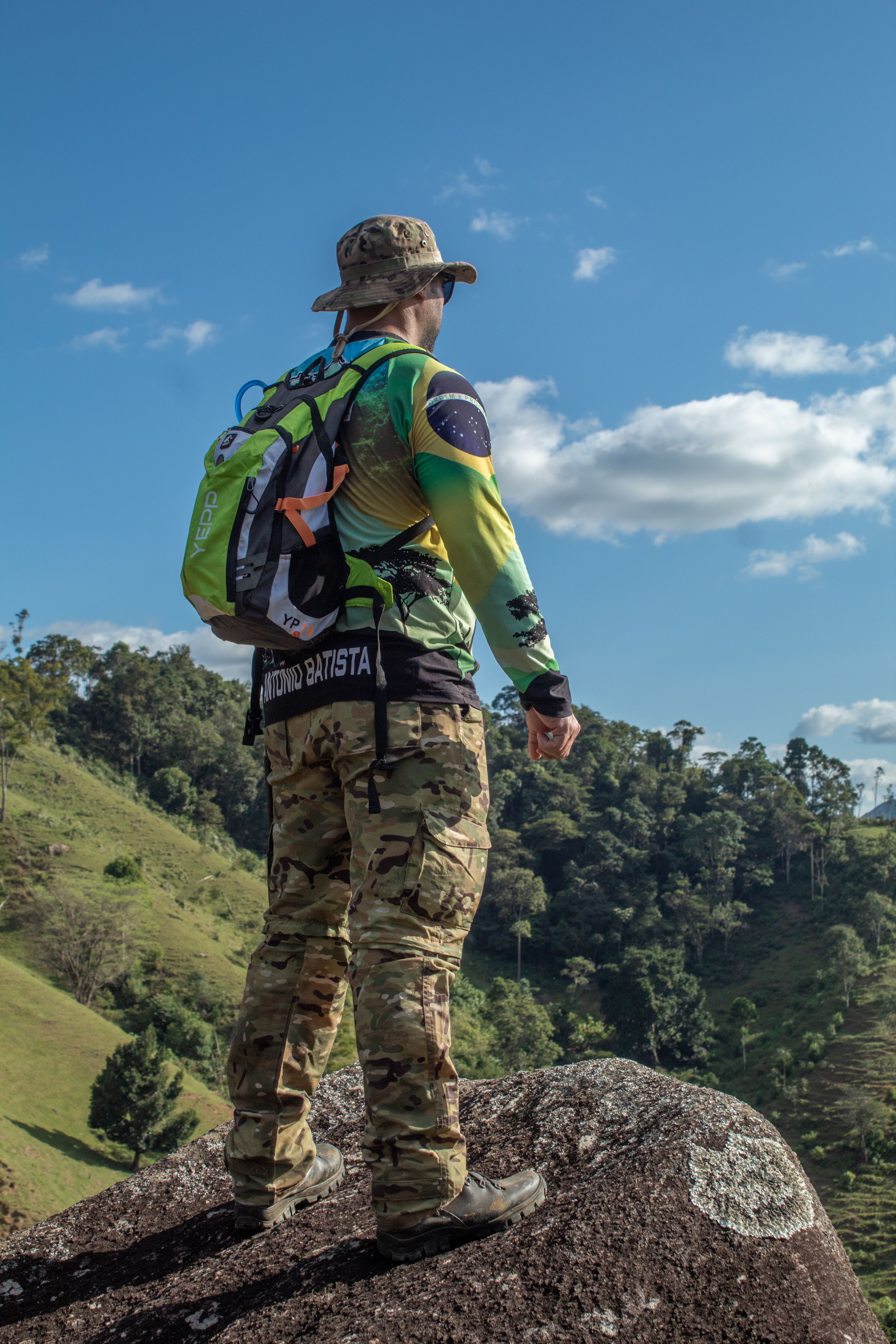 Adventurous hiker with backpack standing on rock amidst scenic landscape.