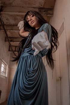 身着蓝色礼服、手戴手套的优雅妇女，站在工业走廊里