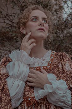 一名身穿复古服装的女子若有所思地在户外摆着姿势，营造出一种喜怒无常的艺术氛围