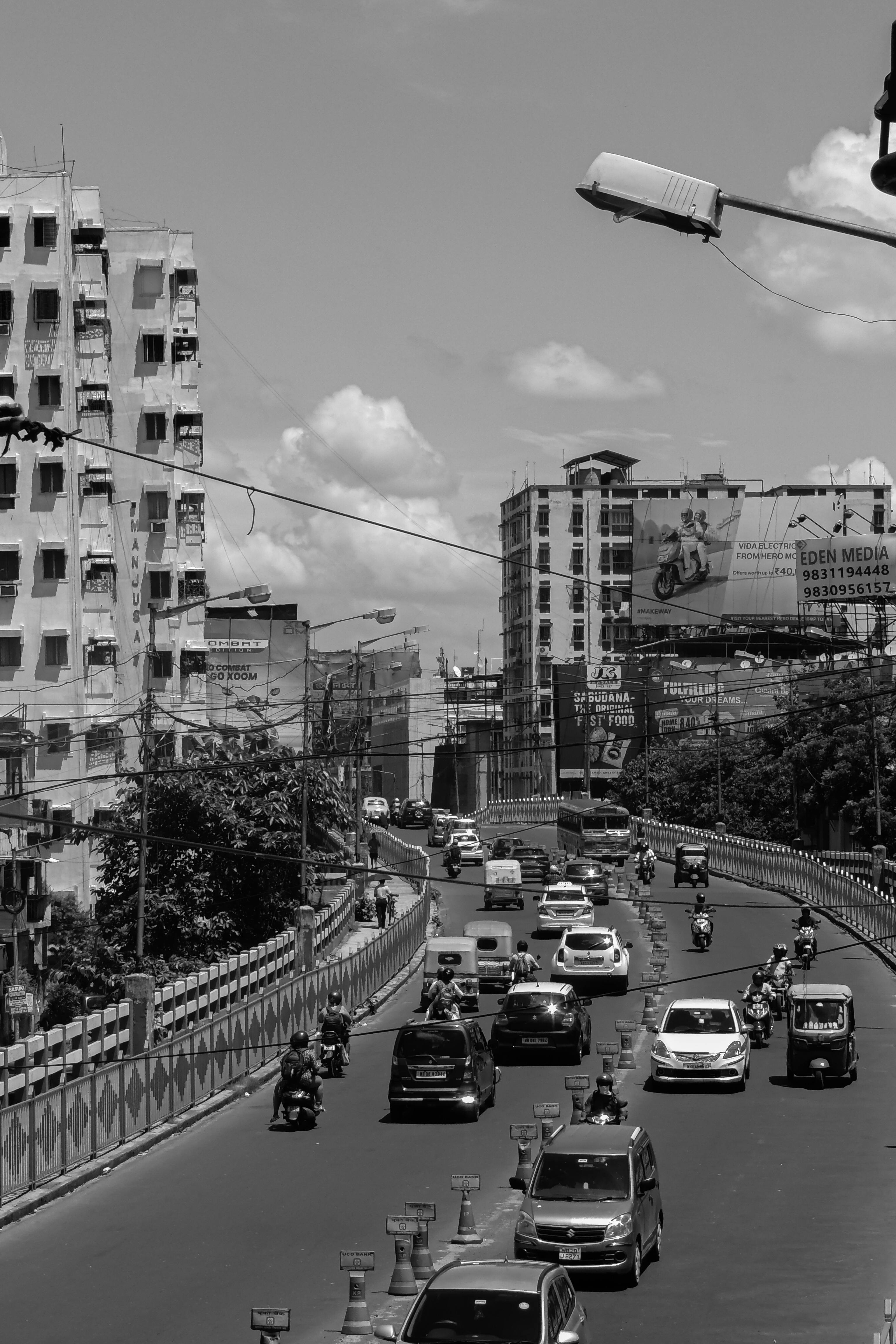 A black and white capture of a bustling roadway in Kolkata, India, showcasing urban life and traffic.