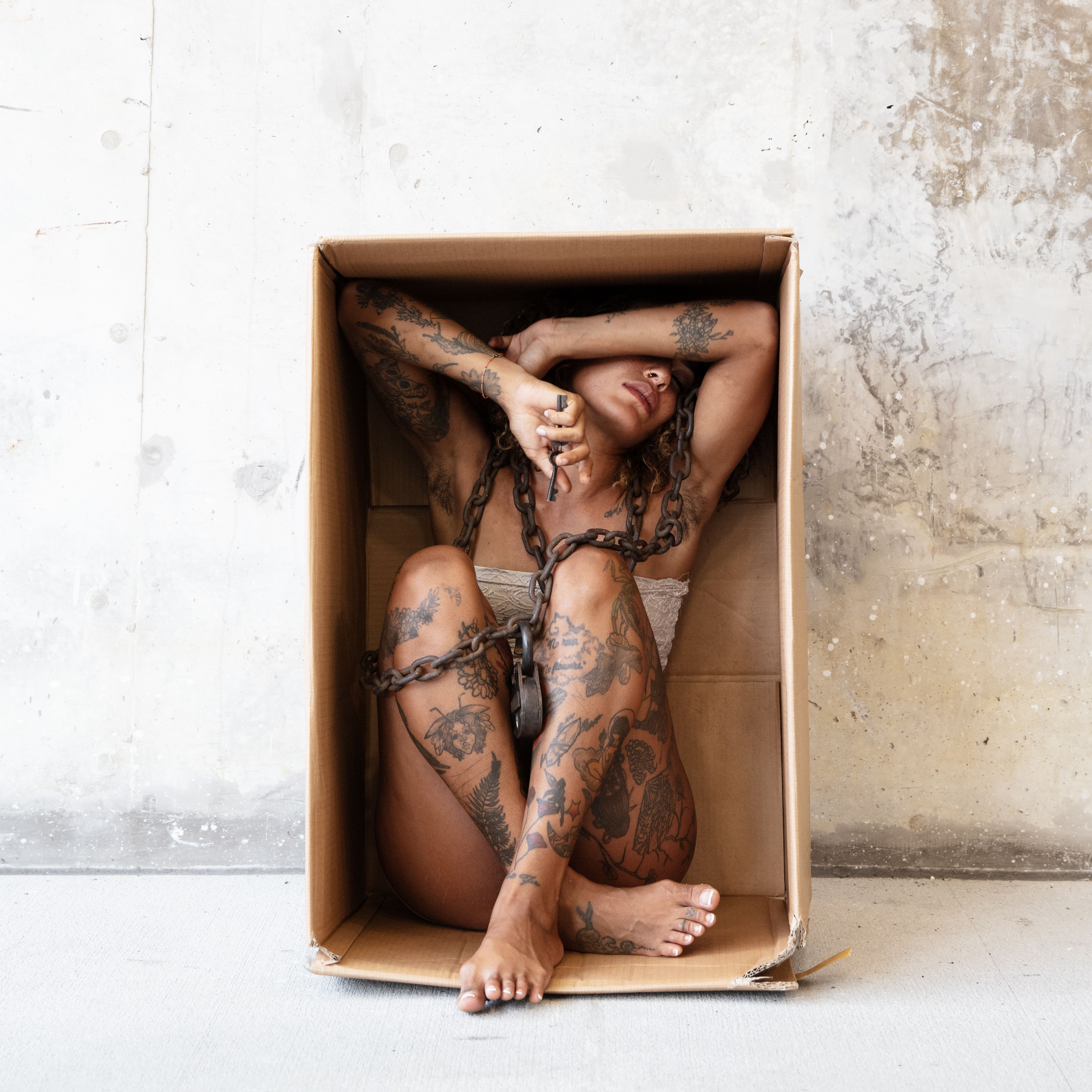 Tattooed Woman in Cardboard Box with Chains