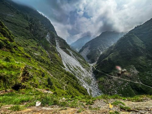 Free Dramatic mountain valley landscape with lush greenery and cloudy sky, perfect for nature enthusiasts. Stock Photo
